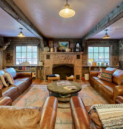 A luxurious, well-lit living room with plush sofas, a central coffee table, warm wood floors, and a ceiling chandelier.