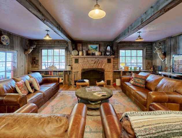 A luxurious, well-lit living room with plush sofas, a central coffee table, warm wood floors, and a ceiling chandelier.
