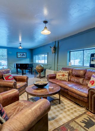 A cozy living room with plush sofas, a warm rug, and a glass wall overlooking a bright, modern interior.