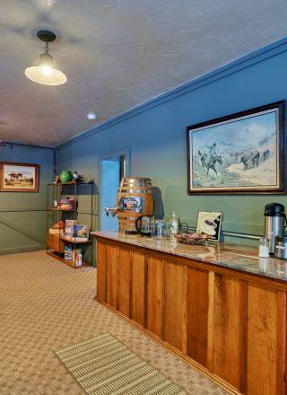 A modern lobby with a curved wooden reception desk, blue accent walls, a mural or screen on the back wall, and a small plant beside the counter.