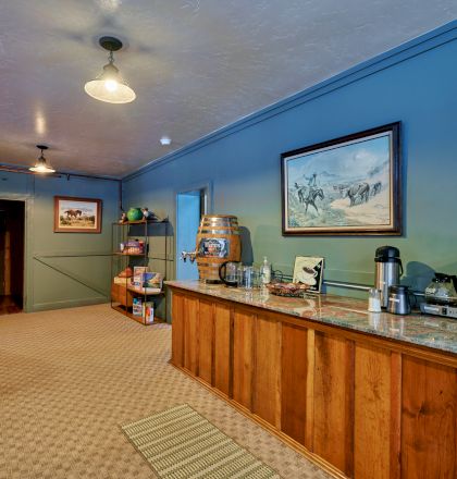 A modern lobby with a curved wooden reception desk, blue accent walls, a mural or screen on the back wall, and a small plant beside the counter.