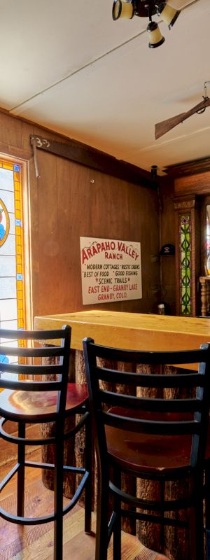 A cozy kitchen and dining area with warm wood cabinetry, a breakfast bar, and natural light from a large window, inviting and homey.