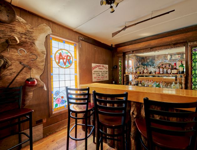 A cozy kitchen and dining area with warm wood cabinetry, a breakfast bar, and natural light from a large window, inviting and homey.