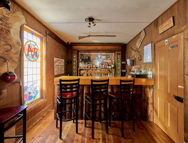 A cozy kitchen with wooden cabinets, a central island, warm lighting, and bar stools, giving a welcoming rustic vibe.