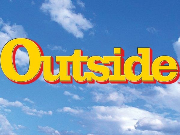 A bright blue sky with fluffy white clouds and a bold yellow-red &ldquo;Outside&rdquo; logo centered across the scene.