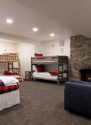 A cozy living room with a stone accent wall, colorful sofas, a fireplace, and warm lighting.