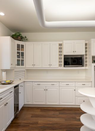 A modern, bright kitchen with white cabinets, a large island, pendant lights, and stainless steel appliances in a clean, airy space.