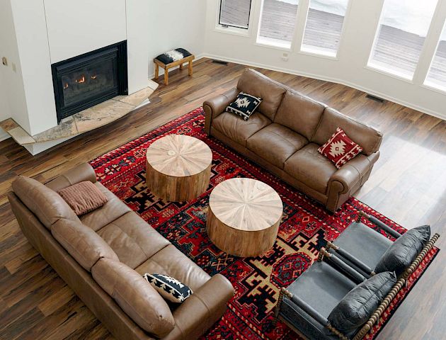 A cozy living room with a red sofa, colorful throw pillows, a coffee table, and a warm fireplace setup, bright natural light, and homey decor ending with a period.