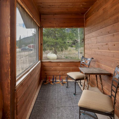 A narrow hallway leads to a bright outdoor patio with wooden ceiling, stones, and potted plants along the path, ending in a cozy seating area.
