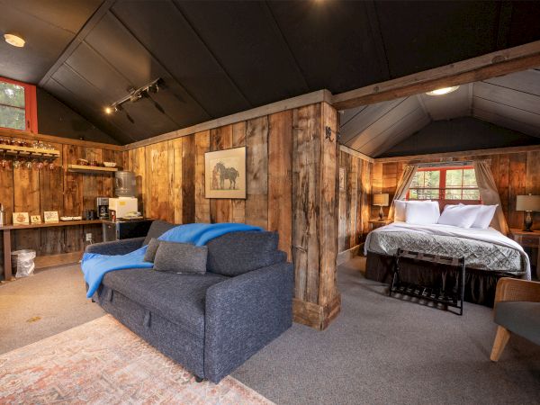 A rustic rustic retreat with a cozy sitting area and a luxurious bed in a timber-framed bedroom, warm lighting, and mixed seating.