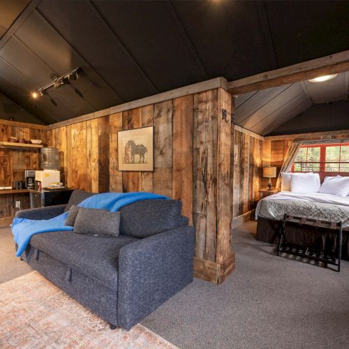 A cozy living room with a dark blue sofa, wooden beams, warm lighting, a fireplace, and a craftsman-style bookshelf&mdash;homey and inviting.