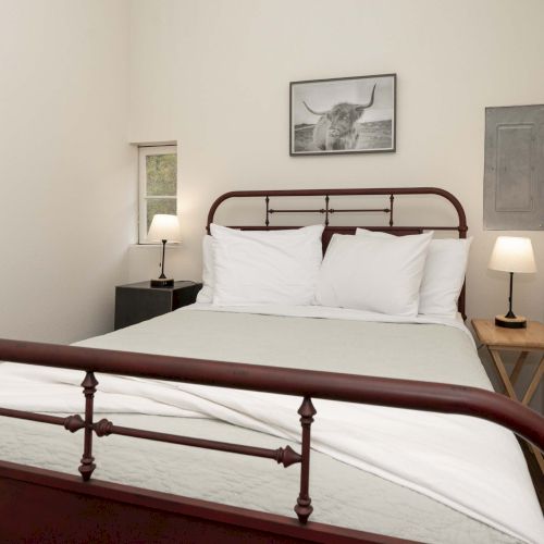 A simple bedroom with a wooden bed, white bedding, nightstands, and a framed picture on the wall, minimal and airy.