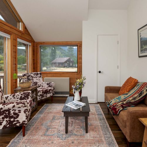 Cozy living room with a sofa, wooden coffee table, plants, and art on the walls; warm lighting and shelves-filled backdrop.