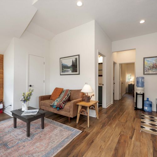 A cozy living room with a wood coffee table, sofa, fireplace, and warm lighting; a bright adjacent dining area with chairs and a large window.