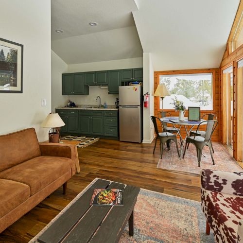 A cozy living room with a wooden coffee table, sofa, and warm natural light streaming through large windows, creating a welcoming ambiance.