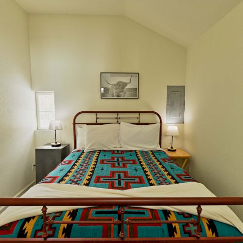A small cozy bedroom with a single bed, greenish walls, a wooden headboard, a window, and a few wall shelves&mdash;neatly arranged with soft lighting.