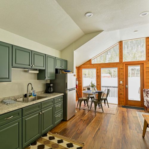 A long, narrow corridor with a greenish wall, wooden floor, and bright open door at the far end.