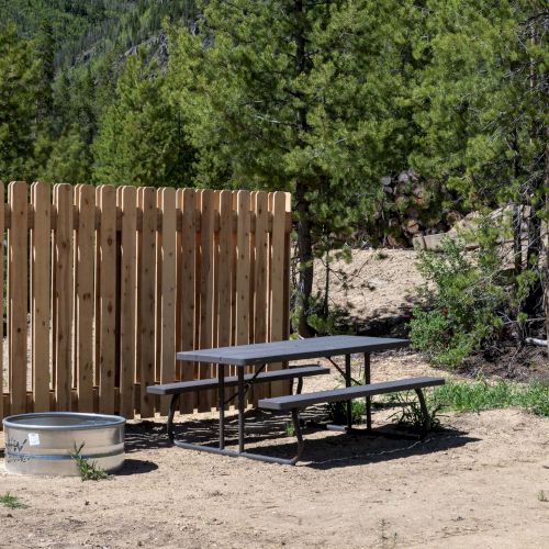 A weathered wooden fence, a toppled chair, and a small scattered pile of debris on the ground in a grassy outdoor area.